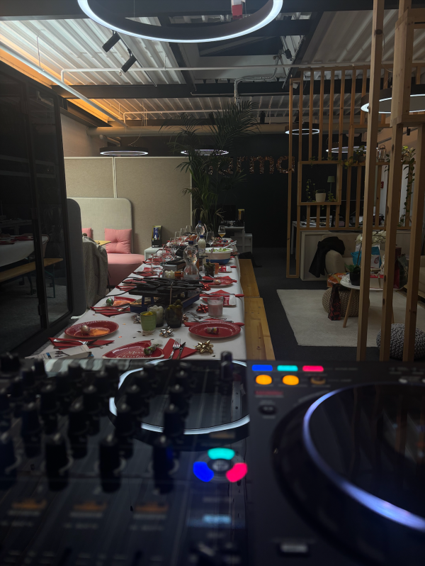 Table dressée pour la soirée de Noël dans les locaux de Clarma à Lausanne, avec raclette prête à être partagée et matériel de DJ au premier plan, créant une ambiance conviviale et festive.