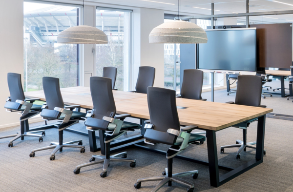 Grey acoustic pendant lights, Sliced model by Luménear, illuminating a bright meeting room featuring a large light wood table and black ergonomic chairs