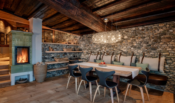 Salle à manger rustique avec suspension en nuage métallique diffusant une lumière chaleureuse, murs en pierre apparente.