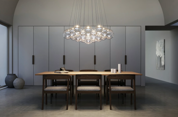 Séjour moderne avec suspension en grappes de sphères en verre diffusant une lumière douce au-dessus d’une table en bois et de chaises assorties.