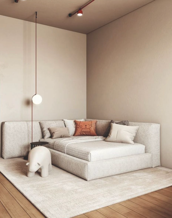 Chambre minimaliste avec lit clair et coussins décoratifs, éclairée par un luminaire suspendu en boule lumineuse et des spots au plafond.