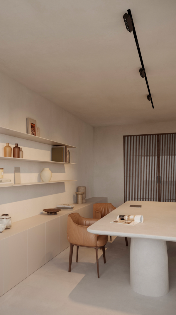 Salle à manger minimaliste avec table claire et chaises en cuir, éclairée par un long rail de spots au plafond diffusant une lumière directionnelle.