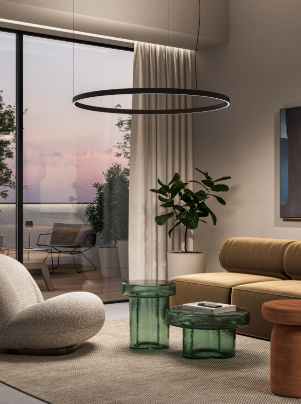 Salon contemporain avec canapé en cuir beige et fauteuil design, éclairé par une suspension circulaire minimaliste au plafond et une lumière naturelle entrant par la baie vitrée.