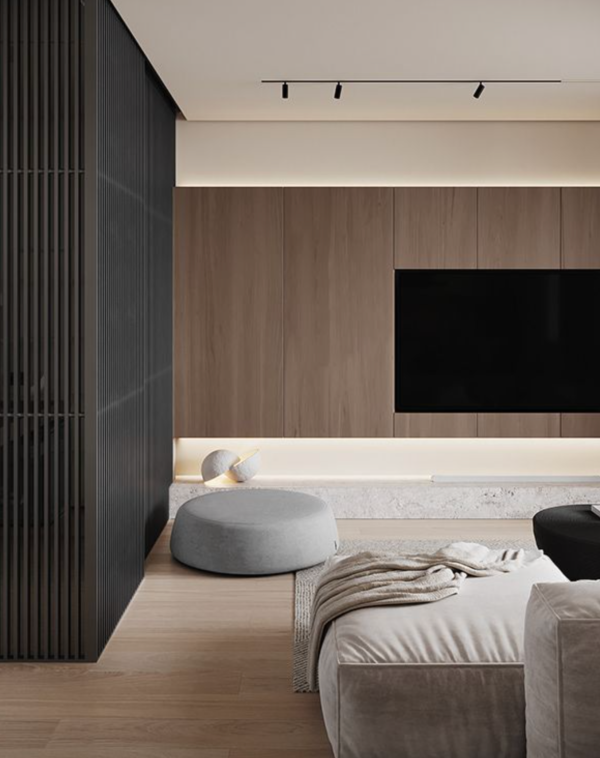 Chambre contemporaine avec lit et pouf gris, éclairée par un rail de spots au plafond, un rétroéclairage mural et une lampe design posée au sol.