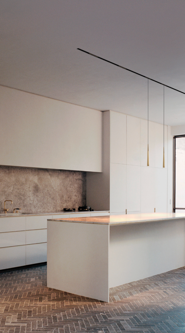 Éclairage minimaliste avec suspensions fines et ligne lumineuse encastrée au plafond d’une cuisine contemporaine.