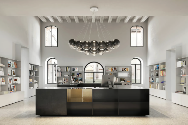 Bright and spacious space with high ceilings, large arched windows, dark modern furniture, and a sculptural designer pendant light.