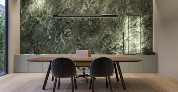 Elegant workspace with side natural light and a backlit green marble wall, centered around a wooden table.