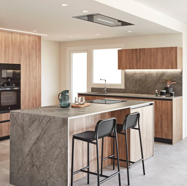 Éclairage encastré au plafond et bandeau lumineux sous les meubles hauts illuminant une cuisine moderne en bois et pierre.