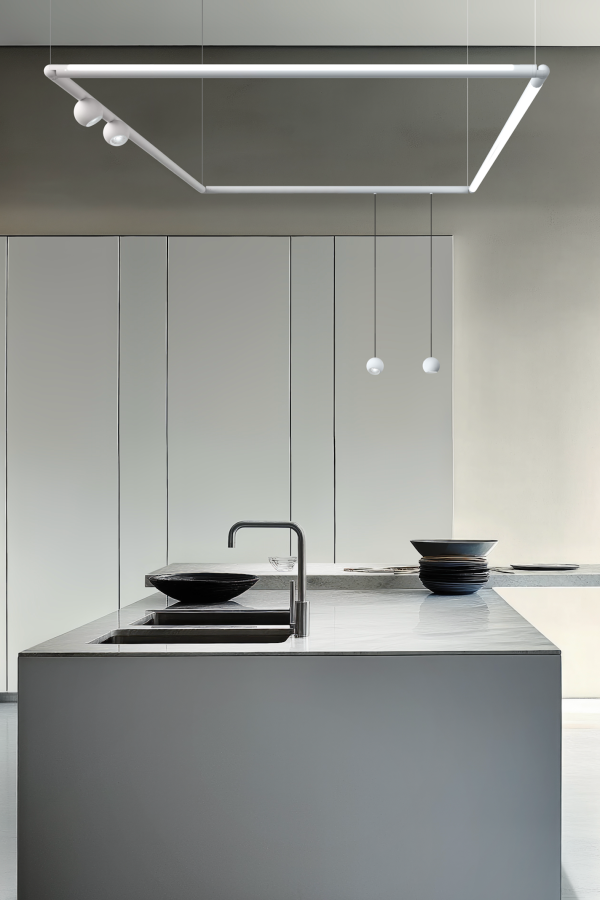 Suspension géométrique moderne avec modules lumineux au-dessus d’un îlot de cuisine minimaliste en marbre.