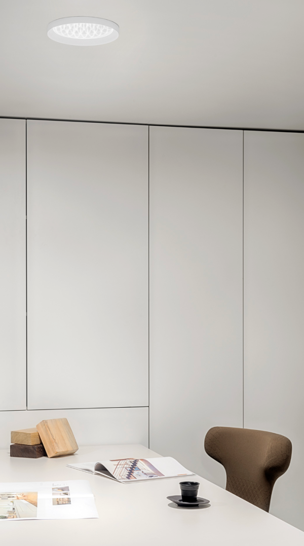 Minimalist workspace with soft ceiling lighting, light furniture, and a clean atmosphere.