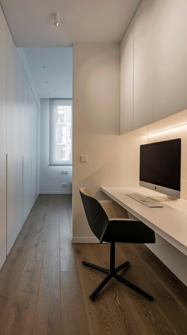 Small, bright, and clean workspace with a built-in desk, subtle lighting, and modern furniture.
