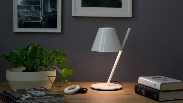 Small white table lamp with an archetypal lampshade balanced on a slanted stem.