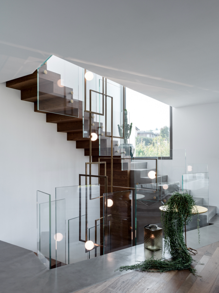 Venicem Mondrian Glass installation at Villa Aghe, Lake Alserio, featuring a woven brass structure with white Murano glass spheres, integrated into a contemporary wooden and glass staircase.