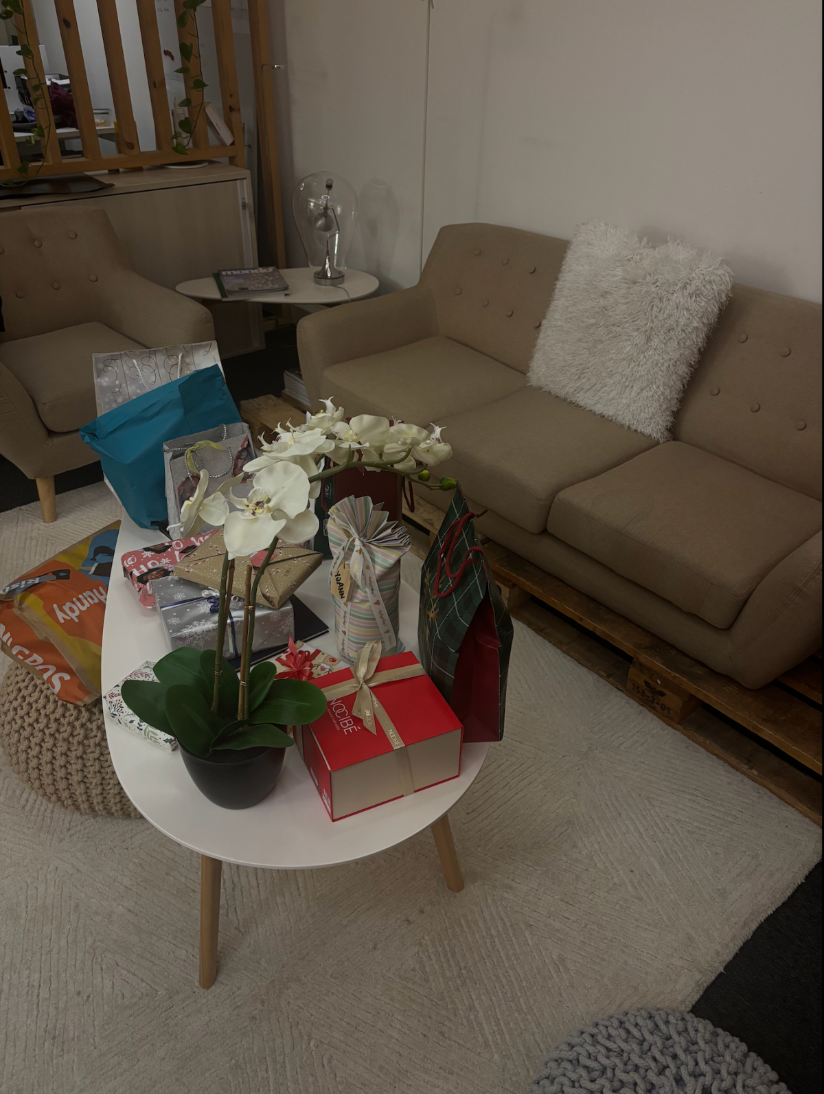 Table basse décorée de cadeaux de Noël dans les locaux de Clarma à Lausanne, créant une ambiance chaleureuse et conviviale dans un espace détente.