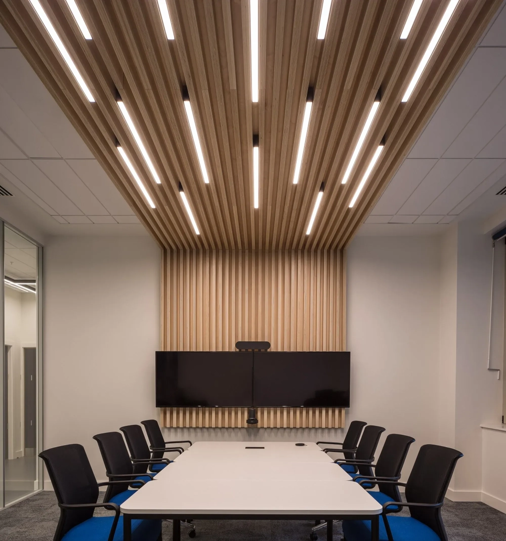 Luminaires linéaires Kalis de Intra Lighting installés au plafond d’un open space moderne, éclairant des bureaux partagés avec vue panoramique sur la ville.