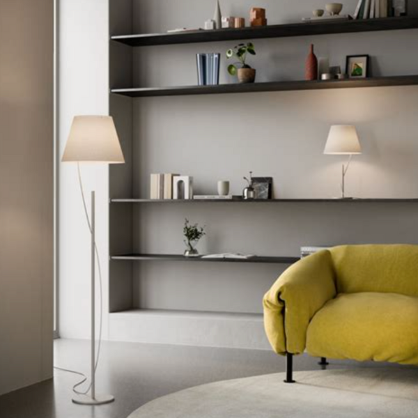 Salon moderne avec lampadaire et lampe de table au design minimaliste, canapé jaune vif et étagères murales décorées.