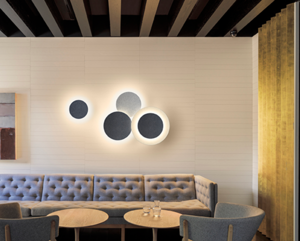 Appliques murales circulaires design diffusant une lumière douce au-dessus d’un canapé dans un espace lounge.
