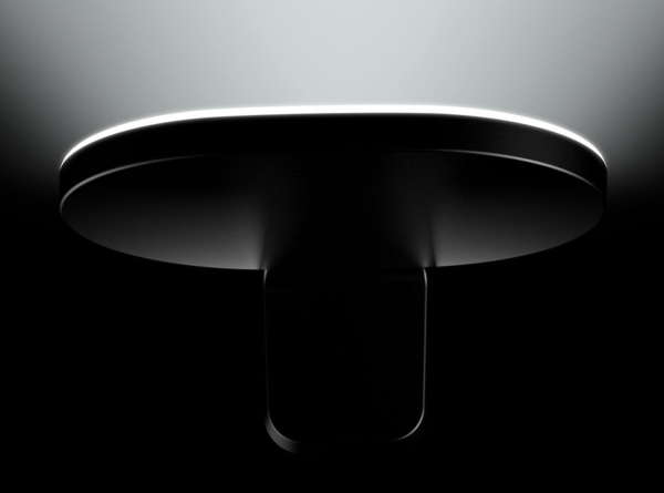 Gros plan sur un luminaire mural noir diffusant une lumière douce en halo vers le haut.