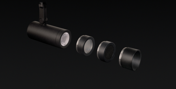 Projecteur noir monté en surface, présenté avec ses différents éléments optiques détachés, permettant un éclairage modulable et précis.