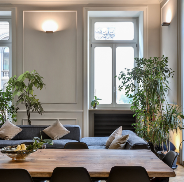 Salon lumineux avec appliques murales diffusant une lumière douce au-dessus d’un canapé et d’une table en bois.