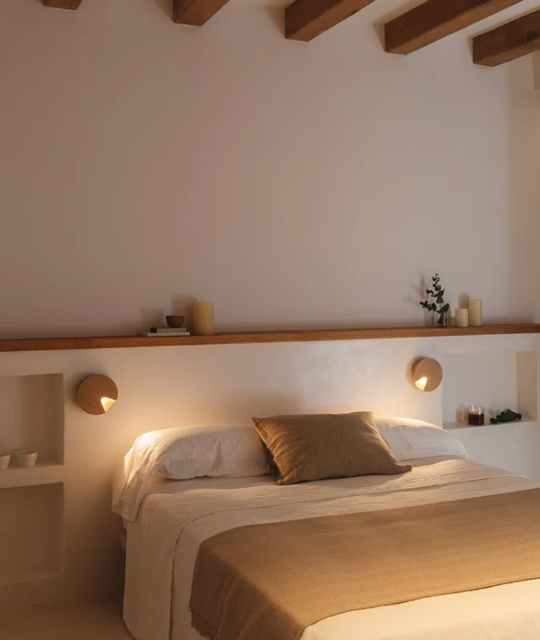 Chambre chaleureuse avec deux appliques murales rondes diffusant une lumière douce de chaque côté du lit.