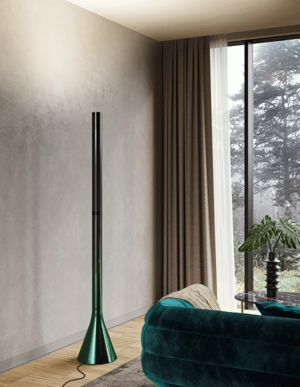 Sleek emerald green floor lamp with a glossy finish, featuring a flared base and a black cylindrical stem, casting indirect light toward the ceiling in a contemporary living room.