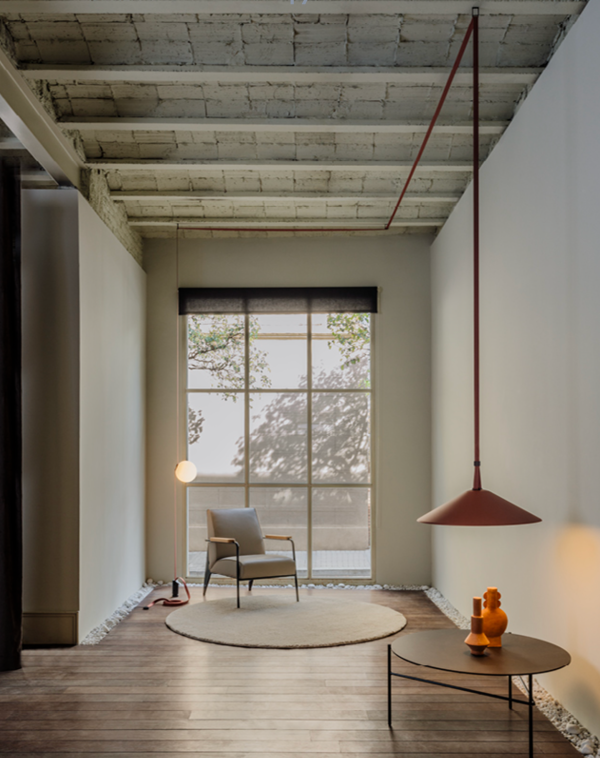 Suspension rouge au design minimaliste éclairant une table basse dans un intérieur épuré.