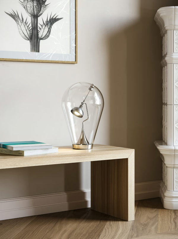Contemporary table lamp featuring a silver metal light fully enclosed within a large transparent bubble-shaped glass diffuser, placed on a light wood console in a minimalist interior.