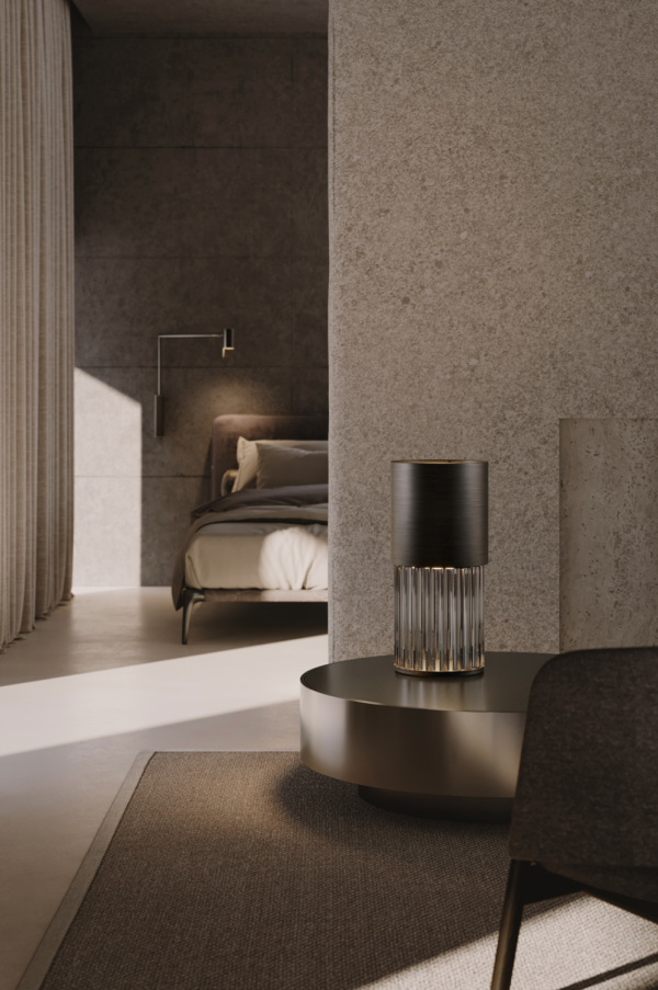Refined table lamp with a dark cylindrical shade and transparent ribbed glass base, casting a soft light, placed on a metallic coffee table in a contemporary interior.