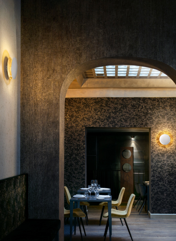 Circular golden wall lights casting a warm glow in an elegant interior space with table and chairs.