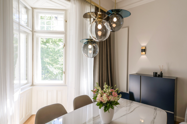Salle à manger élégante éclairée par un trio de suspensions sphériques en verre au-dessus d’une table en marbre blanc.