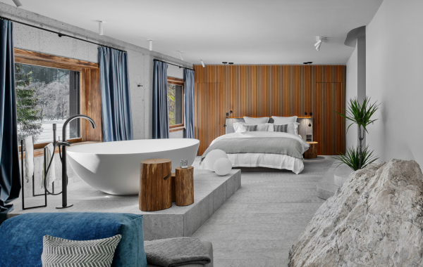 Chambre contemporaine avec baignoire îlot blanche et lit double, éclairée par des spots encastrés blancs au plafond, créant une ambiance lumineuse douce et homogène.