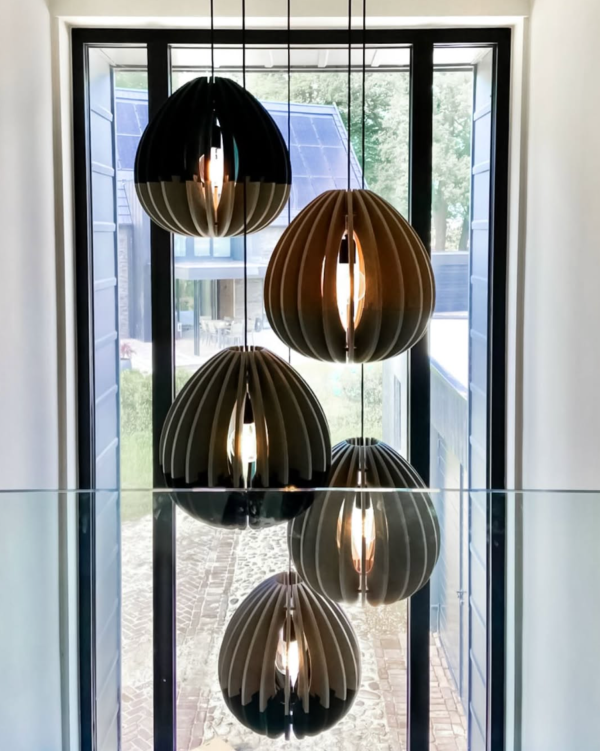 Set of drop-shaped acoustic pendant lights made of vertical slats, lit from within and installed in front of a large window overlooking the outdoors.