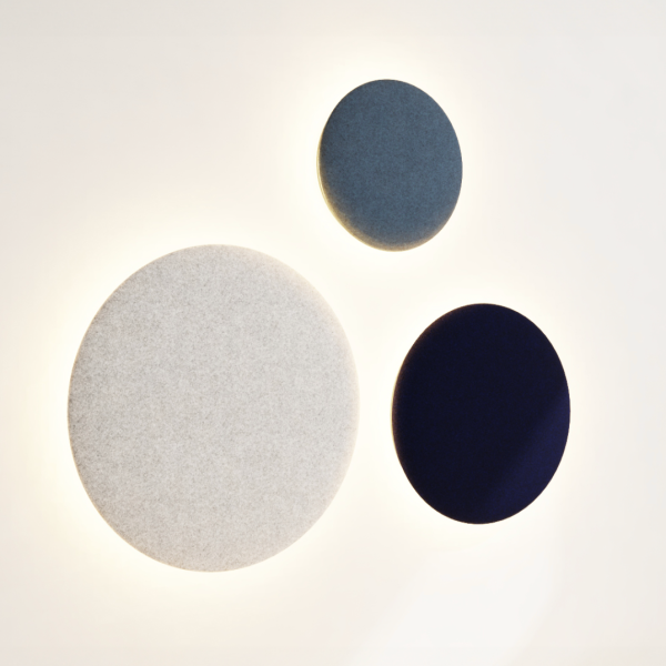 Three round acoustic wall lights in different sizes and colors, emitting a soft backlight against a light wall.