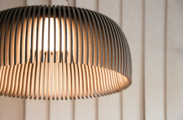 Close-up of a beige acoustic pendant light made of vertical slats, revealing a warm central light, with a background of light-colored panels.