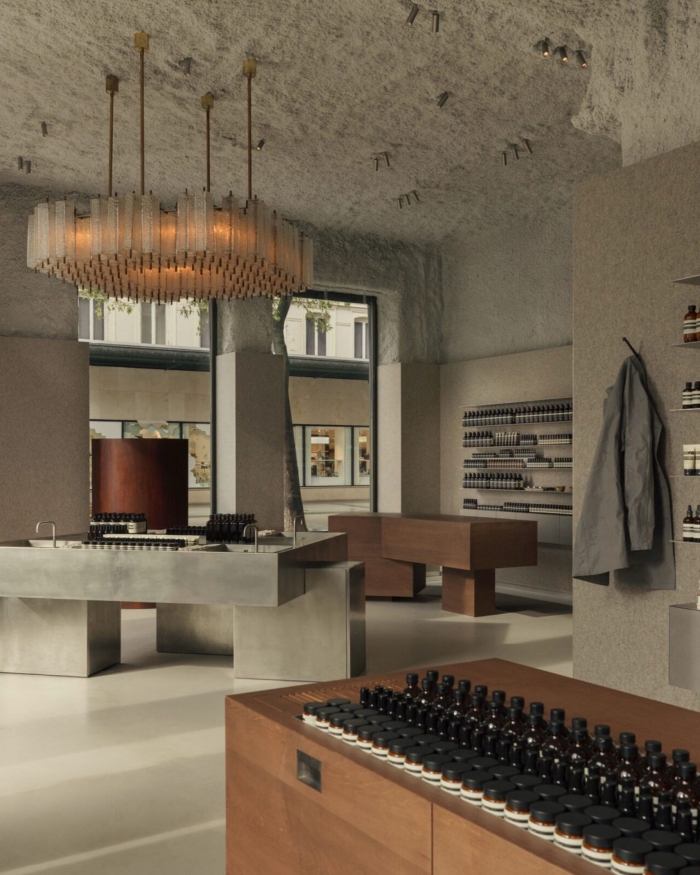 Architectural lighting highlighting a retail space with a textured ceiling, featuring a large pendant light and recessed ceiling spotlights creating a warm atmosphere.