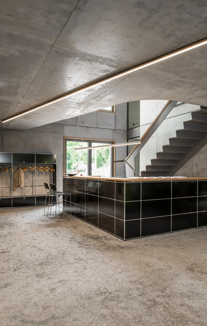 Luminaires linéaires Kalis de Intra Lighting intégrés au plafond et aux parois d’un hall moderne, éclairant un espace élégant avec escalator, ascenseur et finitions bois et verre.